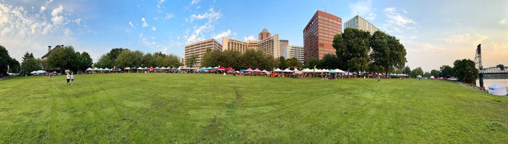 Panoramic image of the Portland Dragon Boat festival showing pop-up tents with the Portland skyline behind